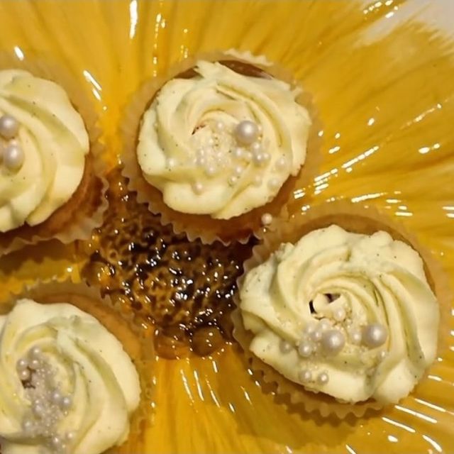 Des cupcakes à la crème vanille pochée, décorés de perles, sur une assiette dorée